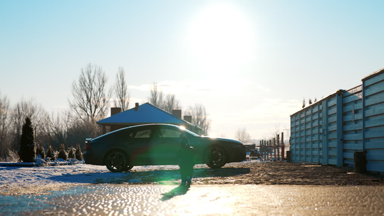 Rear view of a little kid wearing warm clothes outdoors. Baby boy is walking to the car standing in the yard.