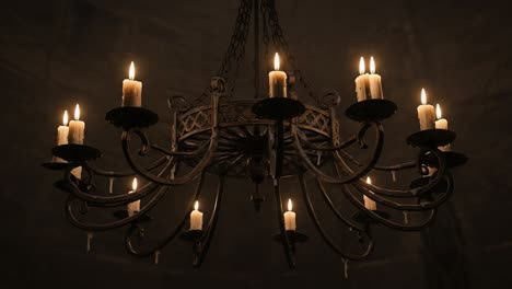 an elegant, flickering candle chandelier illuminating a darkened space with warm glows and intricate metalwork, capturing the essence of vintage lighting aesthetics