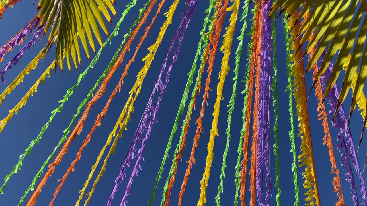 다채로운 리본이 파란 하늘과 종려나무 잎 앞의 거리를 장식합니다.