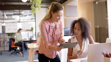 happy diverse businesswomen discussing work and using tablet at office, in slow motion