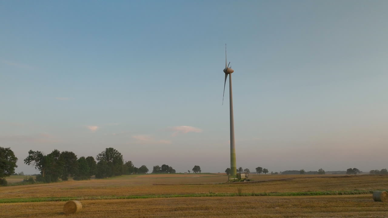 Wind turbine standing tall on farmland with clear sky, renewable energy in rural countryside