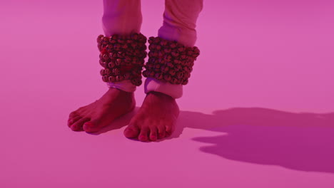 cerca de los pies y las campanas de la bailarina de kathak que realiza el baile vestida con el traje tradicional indio contra un fondo púrpura 7