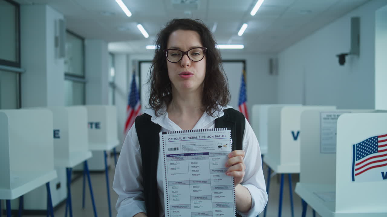 American Female Citizen Speaks on Camera Shows Paper Ballot American Female Citizen Speaks on Camera Shows Paper Ballot Calls for Voting National Election Day in the United States Voting Booths at Polling Place Civic Duty and Patriotism Concept Portrait