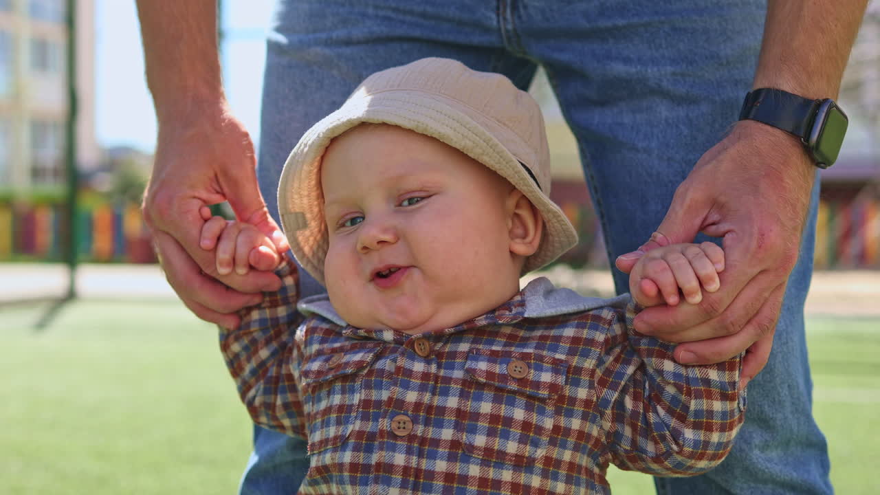 A baby boy learns to walk by holding hands on his mother's hands. Child development. Baby's first steps