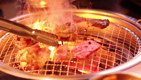 meat grilling on a barbecue with tongs