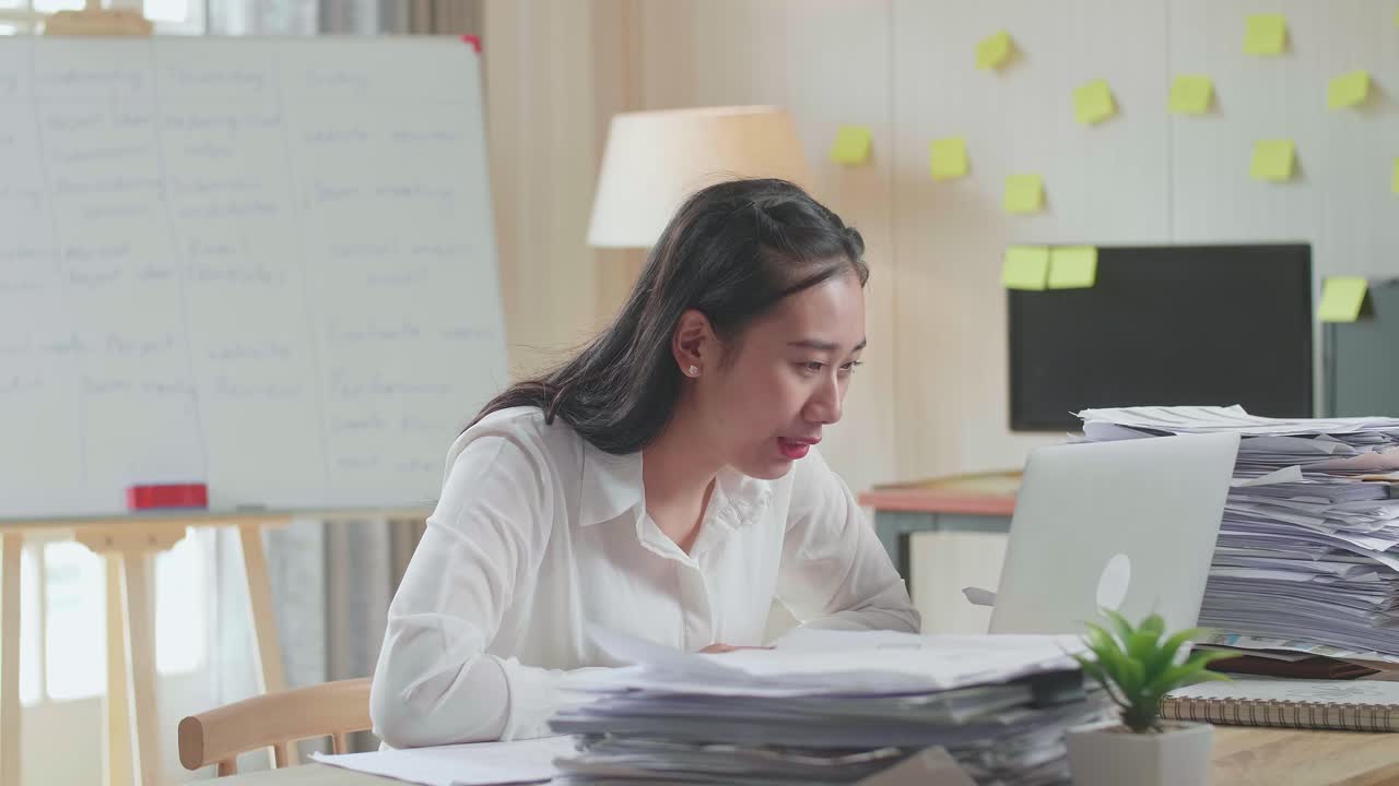 사무실 에서 문서 를 처리 하는 동안 노트북 으로 비디오 통화를 하는 아시아인 여자