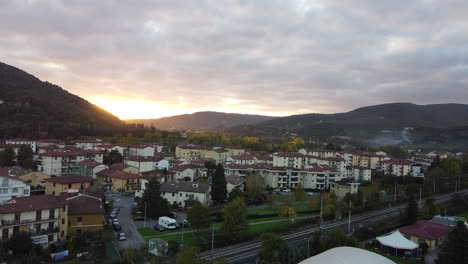 Fast-approaching-aerial-overview-of-Tuscany-province,-Italian-countryside-green-vineyard-covered-hills-sunset-on-a-cloudy-day