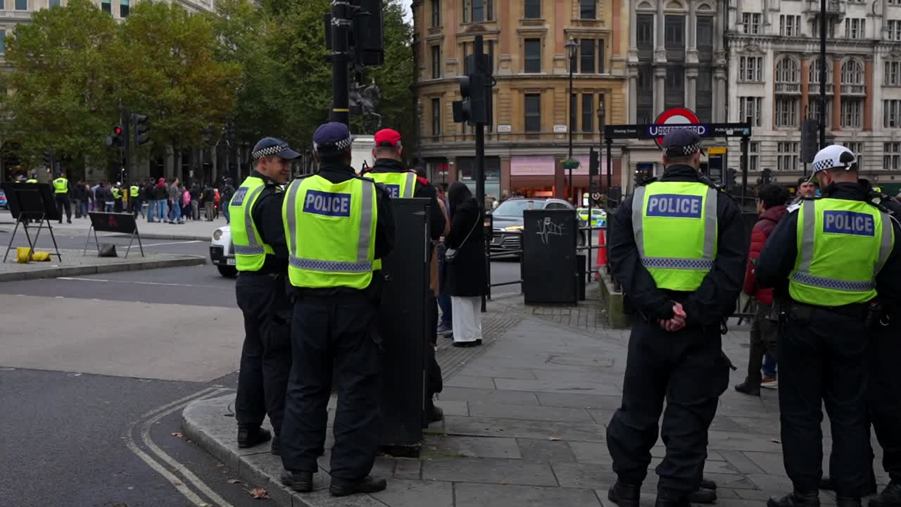 Police monitor crowds at Trafalgar Square near underground exit as people exit tube