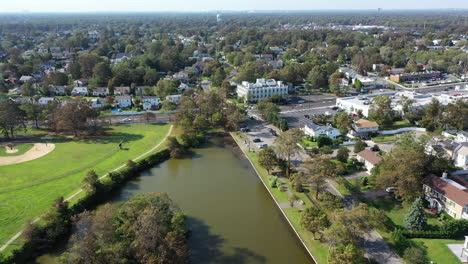 An-aerial-drone-shot-over-a-green-pond-in-a-suburban-neighborhood-on-Long-Island,-NY