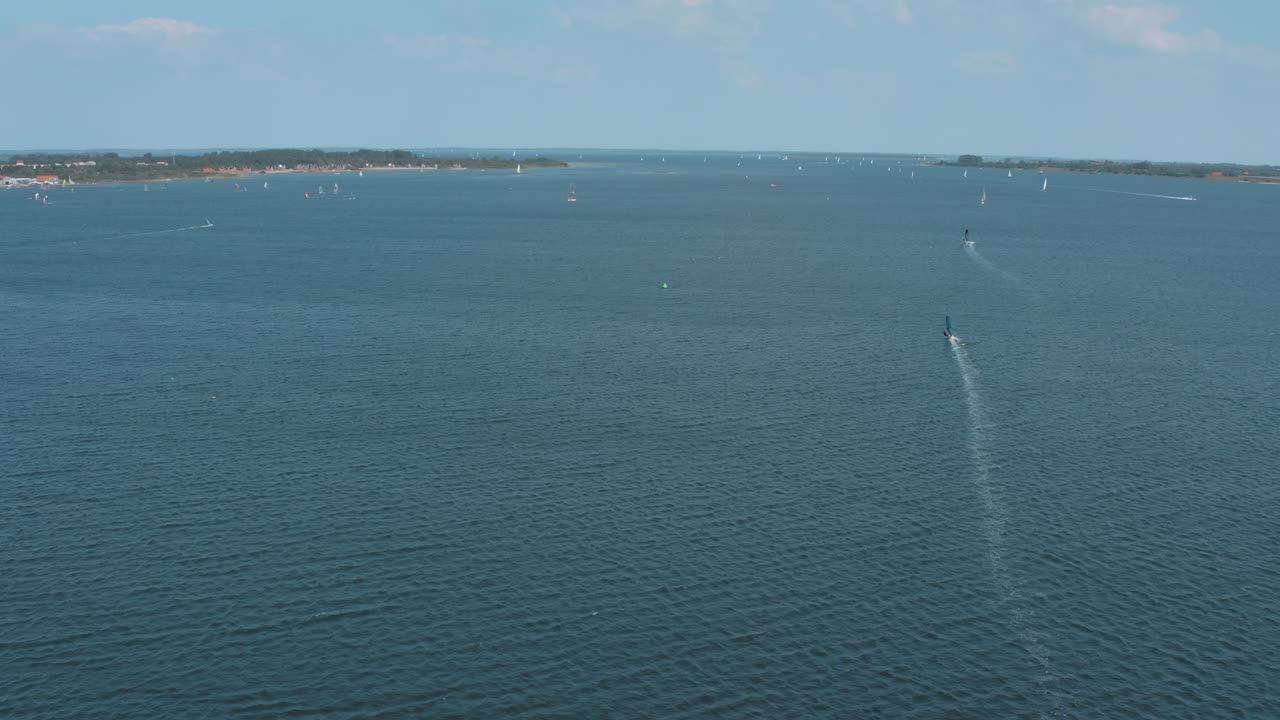 drone - toma aérea de un surfista en un mar azul, ondulado y ventoso en un día soleado con nubes blancas en una isla, 25p
