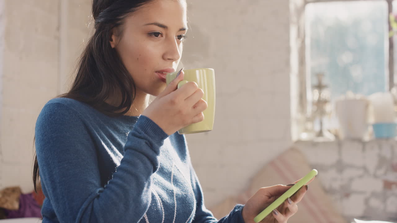아침에 커피를 마시며 집에서 스마트 폰을 사용하는 젊은 학생