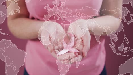 animation of world map over caucasian woman with pink ribbon on pink background