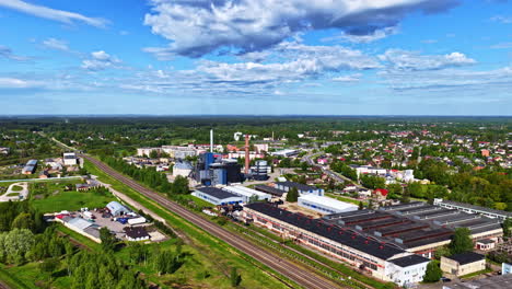 industrial plant and rail lines next to green suburban neighborhood, clear sunny day