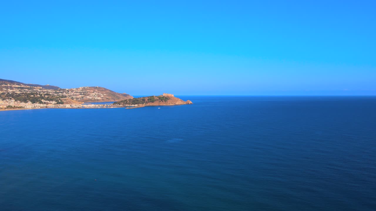 A beautiful view of the ocean with blue skies and mountains in the distance. It's a clear day providing excellent views from a boat or a coastal area.