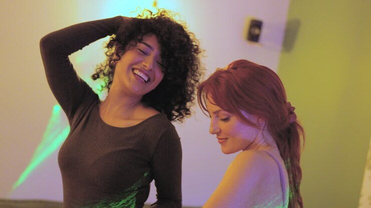 Sensual women dancing together in a home party