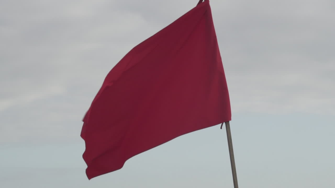 bandera roja ondeando en el cielo despejado - advertencia de peligro - primer plano