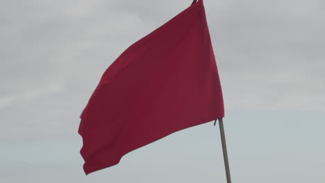 red flag waving on clear sky - warning of danger - close up shot