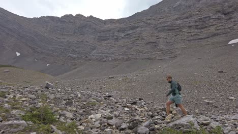 Hiker-walking-through-mountain-amphitheater-followed-Rockies-Kananaskis-Alberta-Canada