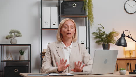 caucasian calm mature businesswoman in suit meditating after using laptop at home office desk