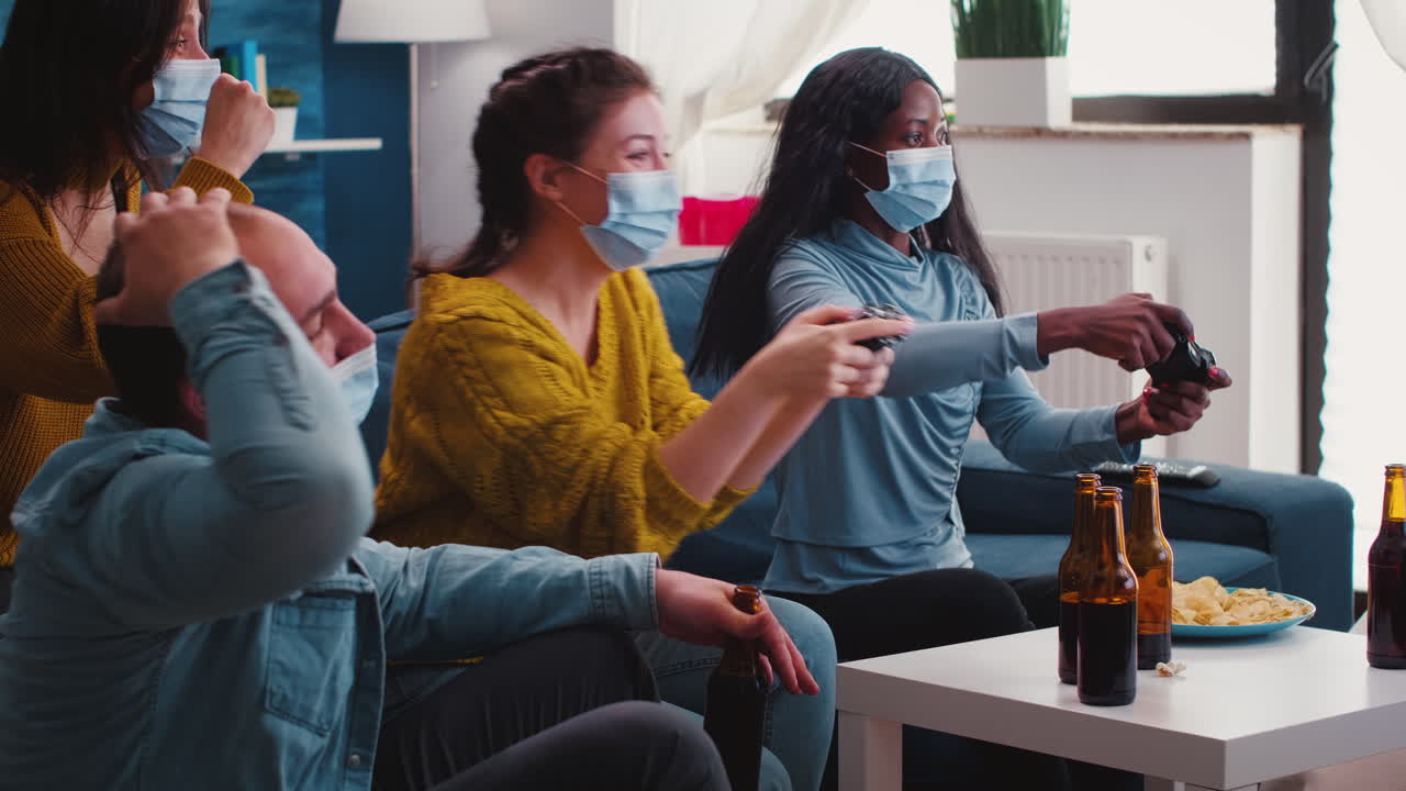 Excited multiracial gamer women sitting on couch playing video games