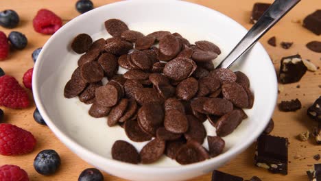 pouring chocolate cereal on a bowl of yogurt
