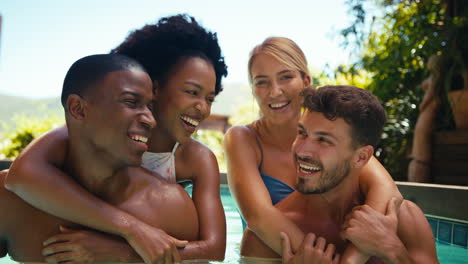 Retrato-De-Amigos-Multiculturales-De-Vacaciones-En-La-Piscina-Con-Hombres-Llevando-A-Mujeres-A-Cuestas