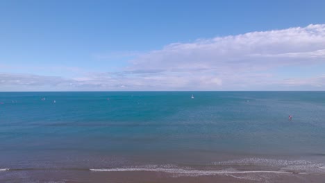 male walks off towards waters on beautiful lonely beach, revealing drone shot