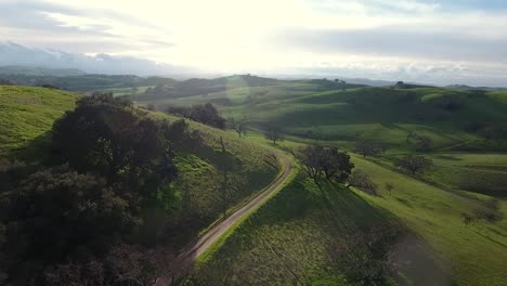 aerial view drone flying over green rolling hills on a sunny day