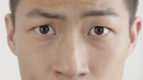 close up young asain man faces showing various emotions eyes looking at camera white background