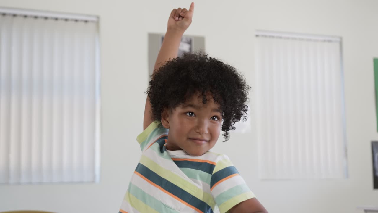 Teacher asking question African child raising right hand in classroom at desk showing readiness