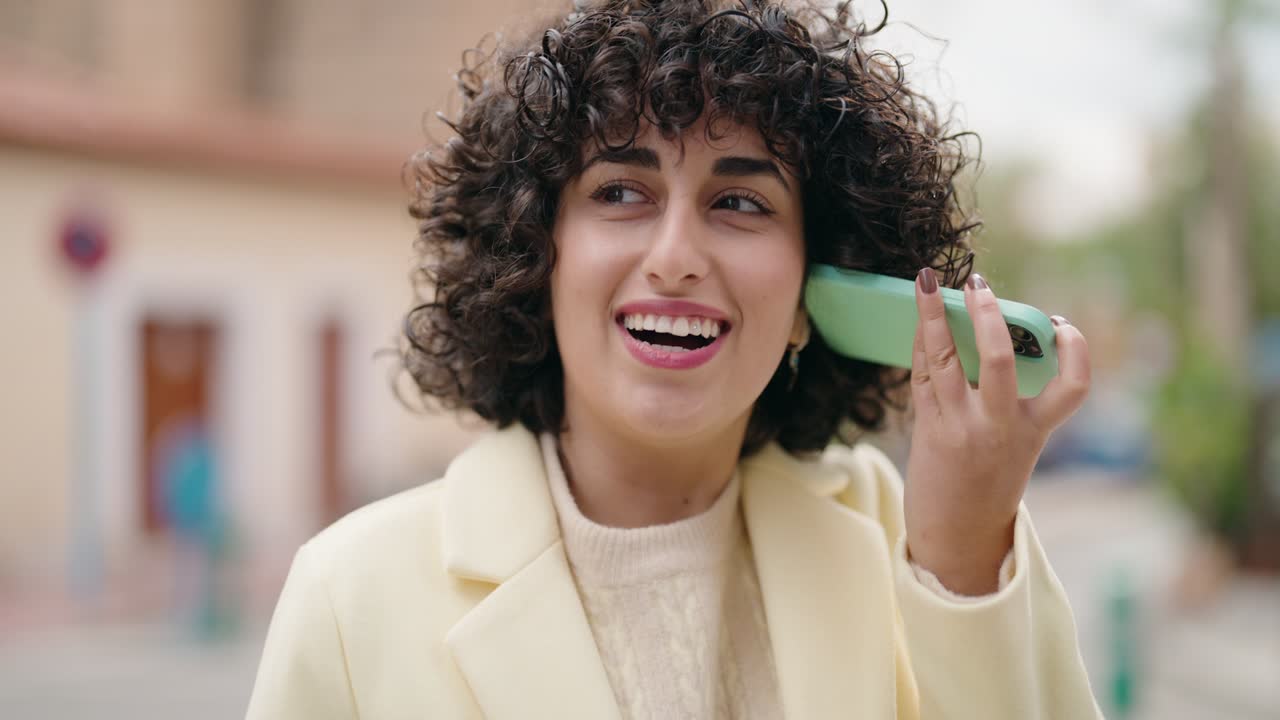 Giovane donna sorridente fiducioso messaggio audio d'ascolto dallo smartphone in strada