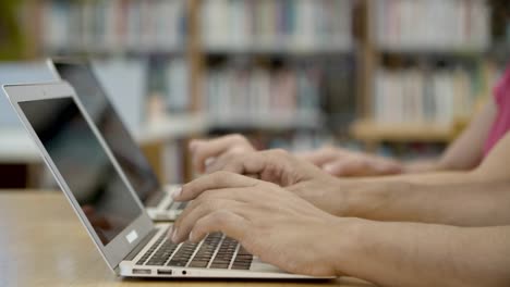 toma en cámara lenta de estudiantes escribiendo en computadoras portátiles en la biblioteca