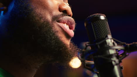 artist records his voice on microphone in home studio singing a song