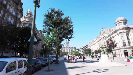 cars parked along the ornate buildings of praça da liberdade in porto under a clear blue sky