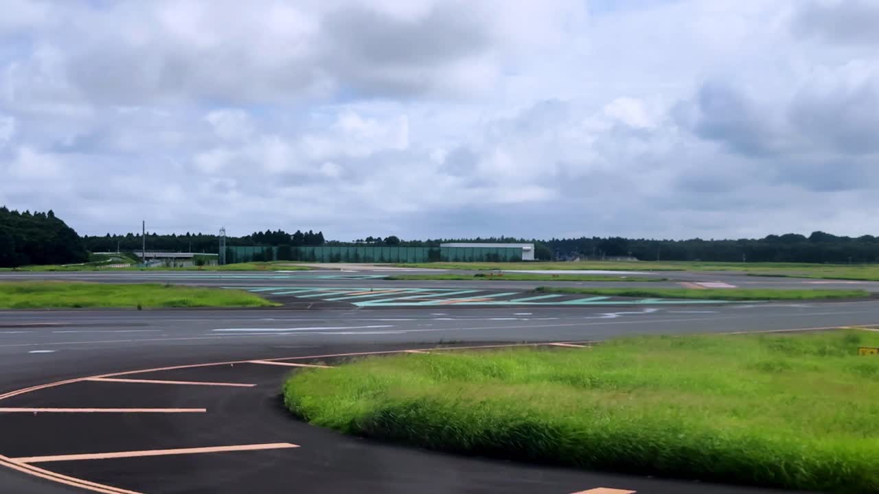 View from a plane on the runway, ready for takeoff on a cloudy day with green fields nearby