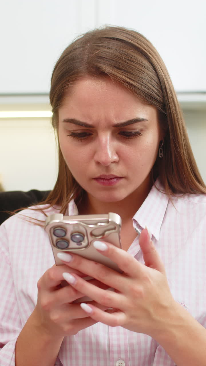 Giovane donna legge una lunga chat di lavoro sullo smartphone, si mette le mani in faccia e digita una risposta per risolvere un conflitto in condizioni di stress