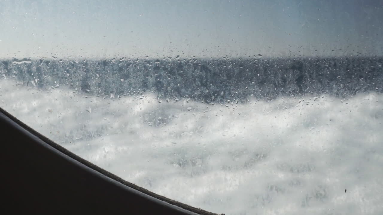 niebla de agua en la ventana del portillo del barco mientras viaja en el océano, olas en el fondo, cámara lenta