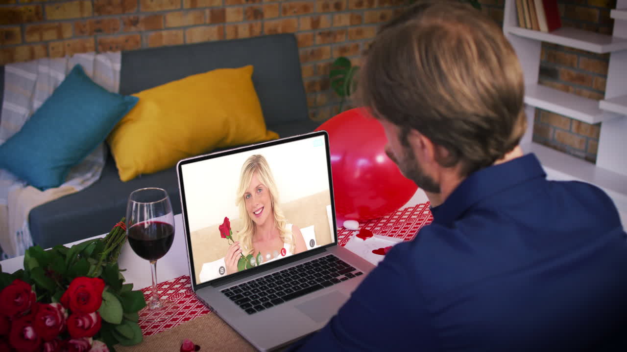 Coppia caucasica a un appuntamento di San Valentino in videochiamata: donna sorridente sullo schermo del portatile che tiene una rosa.