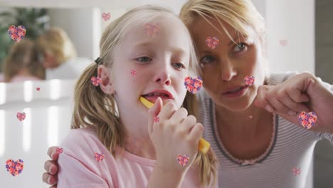Animation-of-flower-hearts-over-caucasian-mother-and-daughter-brushing-teeth