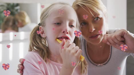 animation of flower hearts over caucasian mother and daughter brushing teeth