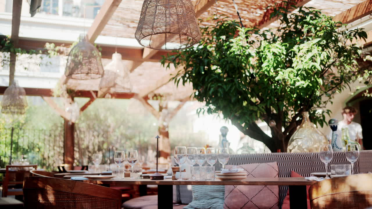 Interior of a chic outdoor restaurant with wooden furniture, glassware, and soft light