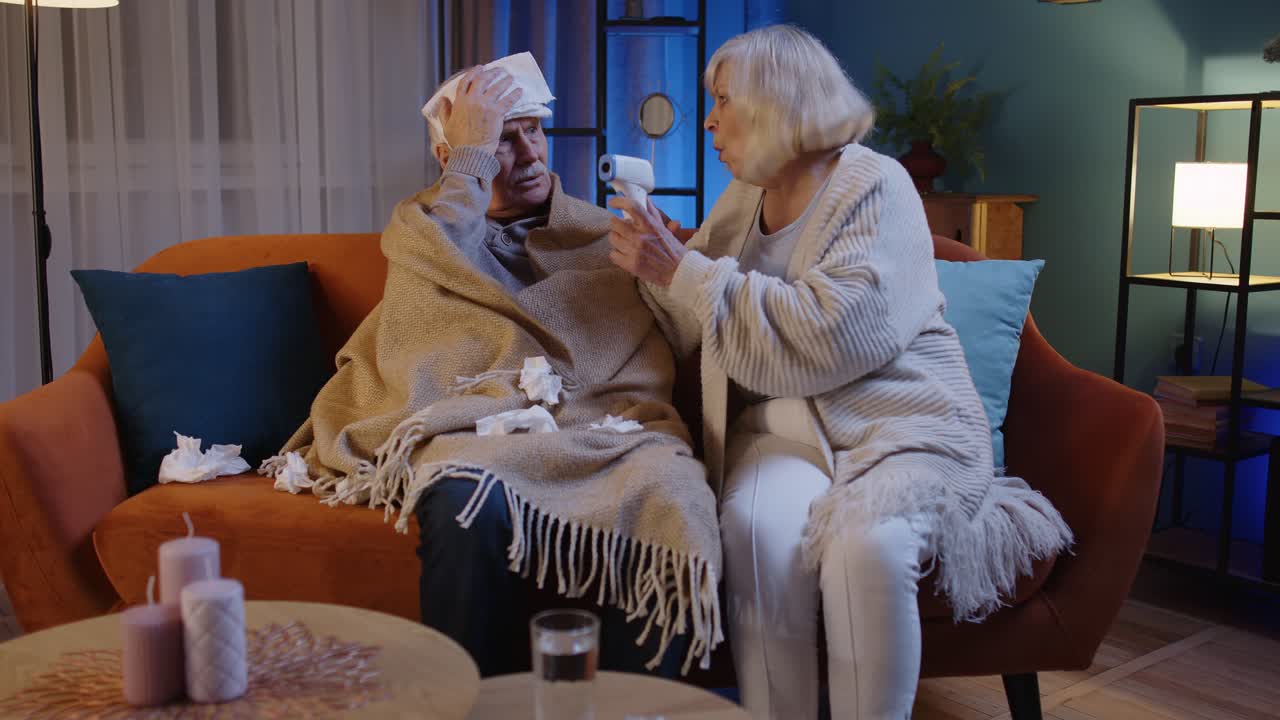 코로나 바이러스 봉쇄 기간 동안 고령 부부는 비접촉 디지털 온도계를 사용하여 온도를 측정합니다.