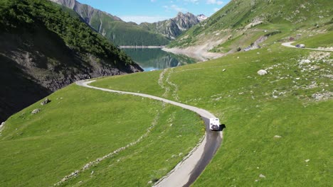 rv motorhome drives winding road to lac de grand maison in french alps - aerial