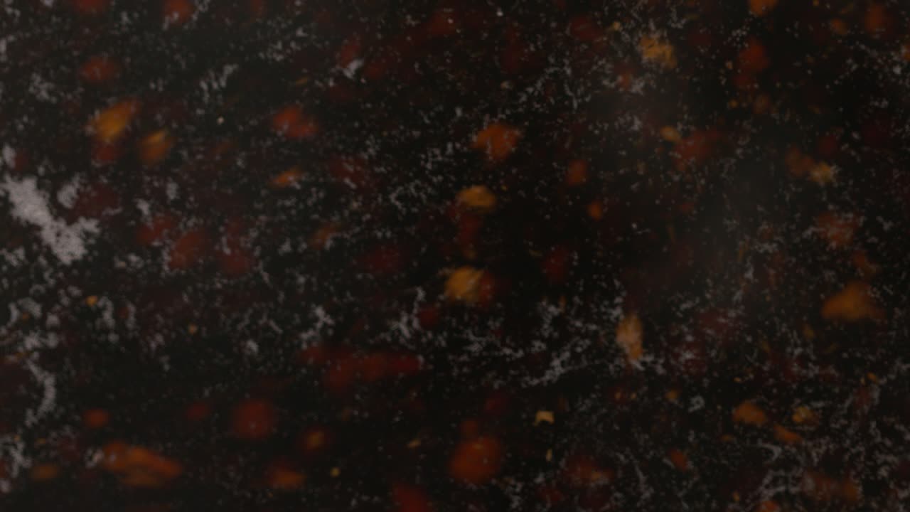 A detailed close-up, slow-motion of tea particles boiling in water with steam, preparing a hot drink