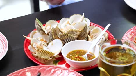 enjoying boiled ark clams with spicy sauce in phuket, thailand