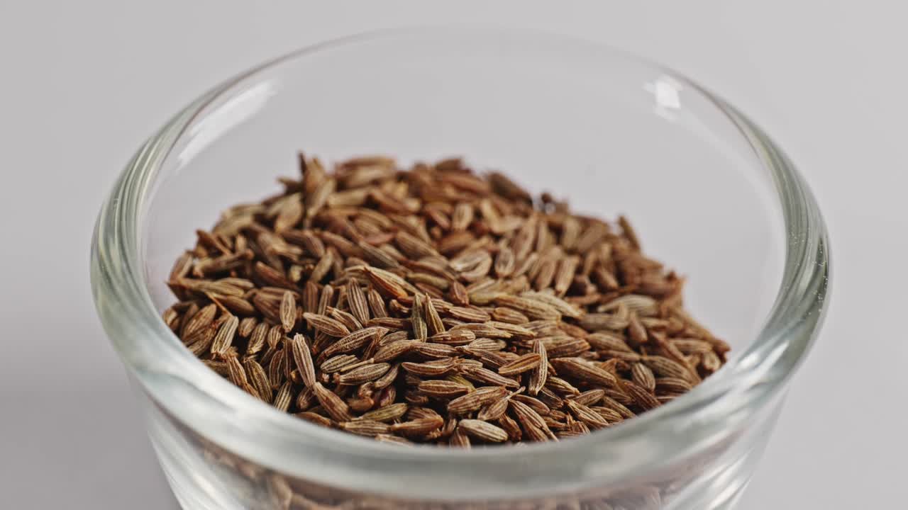 cumin seeds or jeera in small glass bowl, closeup, 4k, parallax shot.