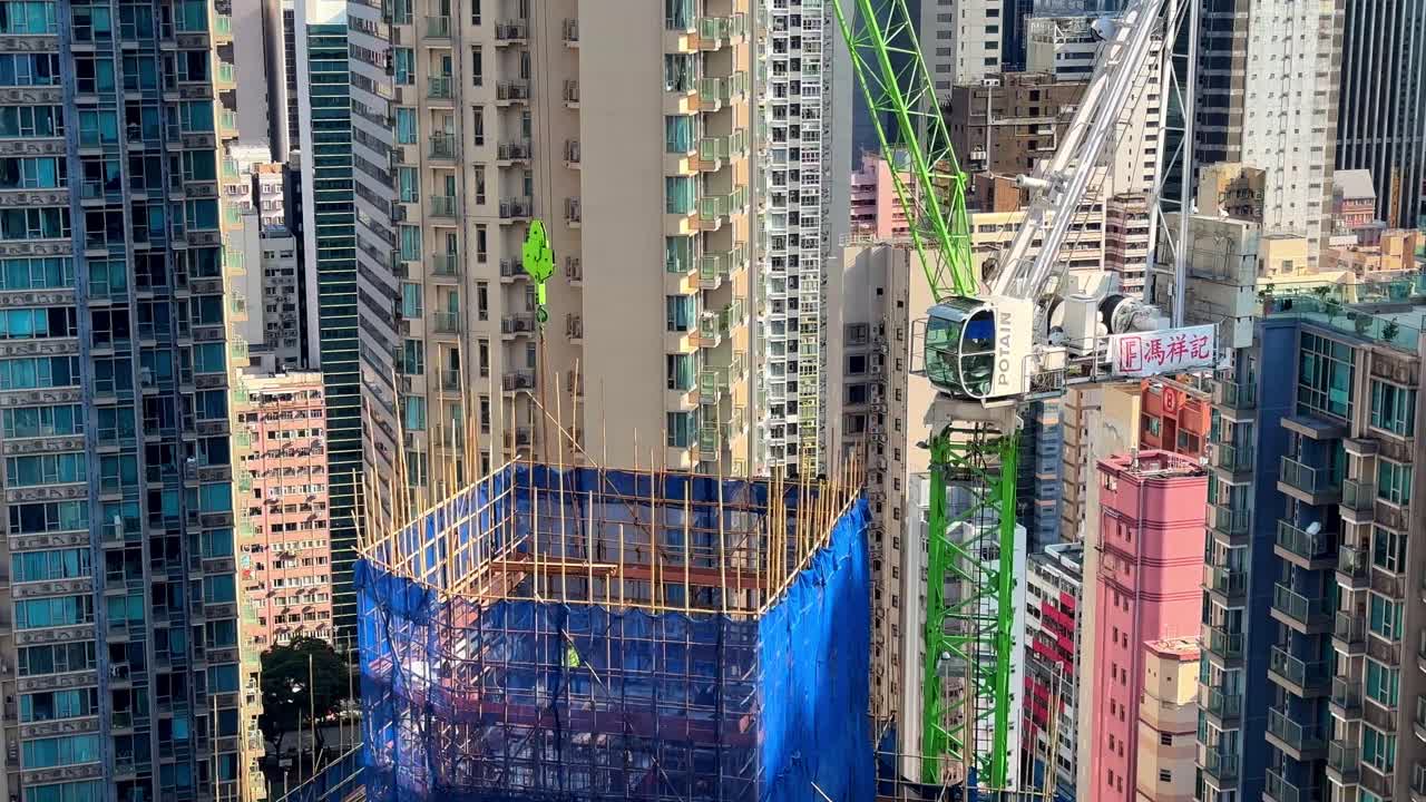 Tower Crane Lowering Wooden Planks onto Skyscraper Construction Site in Hong Kong's Residential Area