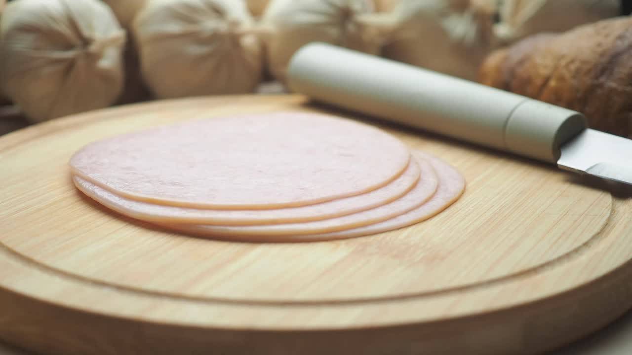 Skinkeskiver på et skærebræt med hvidløg i baggrunden