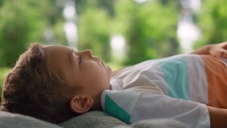 relaxed guy lying on blanket closeup. calm boy look up lounging on green grass.