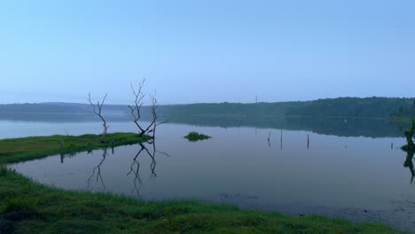 Morning-calm-lake-,-before-sun-lake-reflecting-the-atmospheric-effects-of-the-sky-and-surrounded-by-misty-fogs